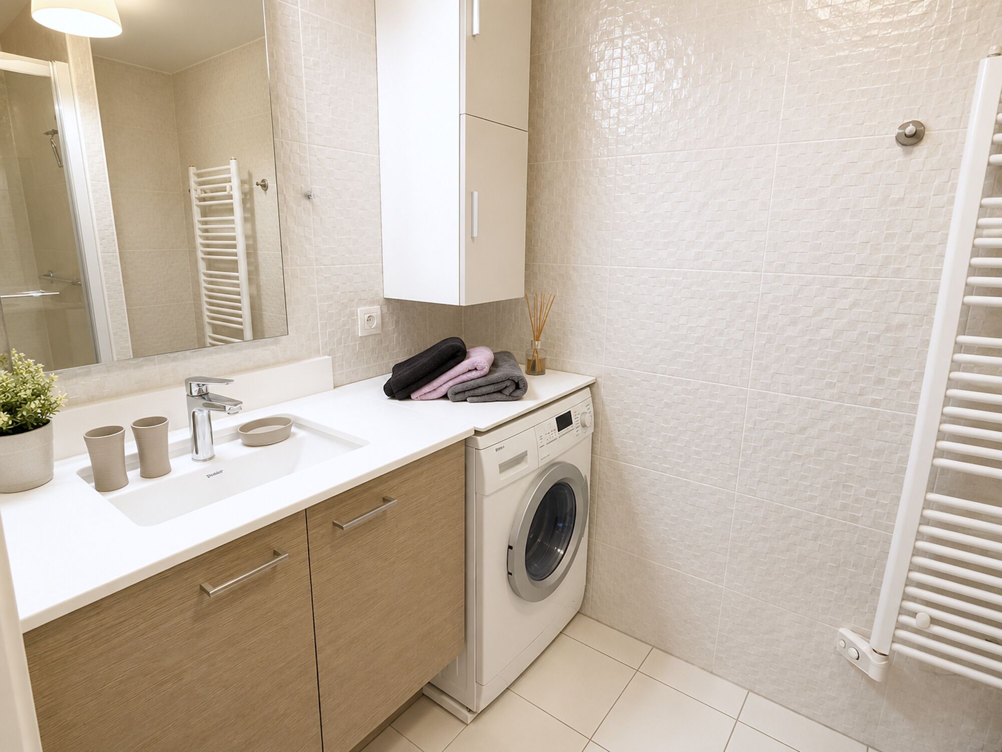 A modern bathroom with a built-in washing machine, a sink, and a towel rack.