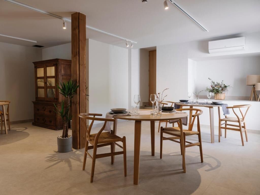 A dining area with a round table, wooden chairs, a cabinet, and a potted plant.