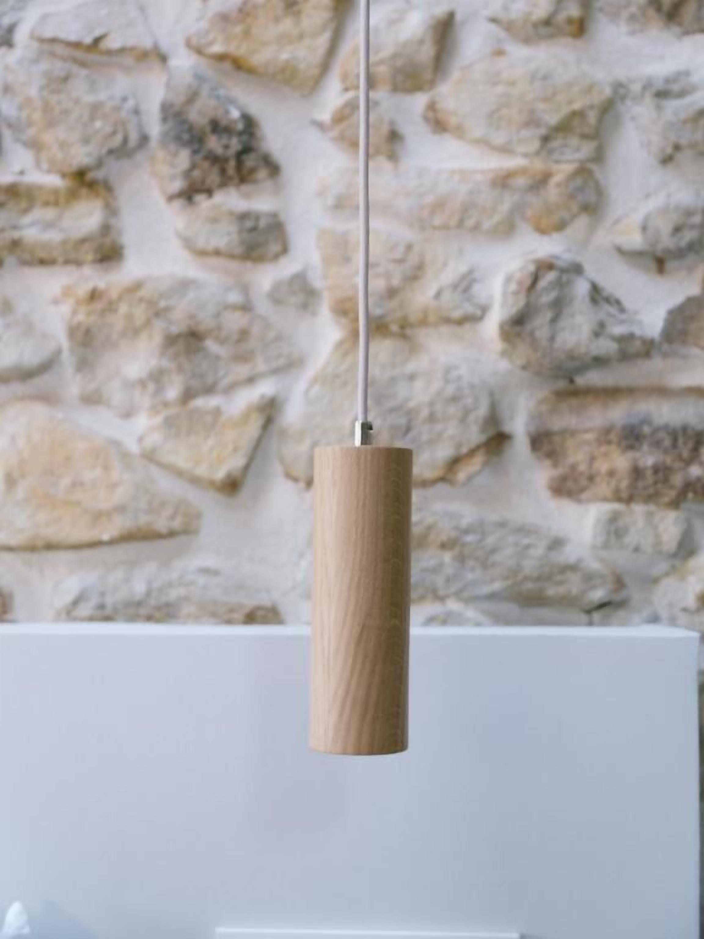 Un luminaire suspendu, avec un abat-jour et une base en bois, fixé au plafond.