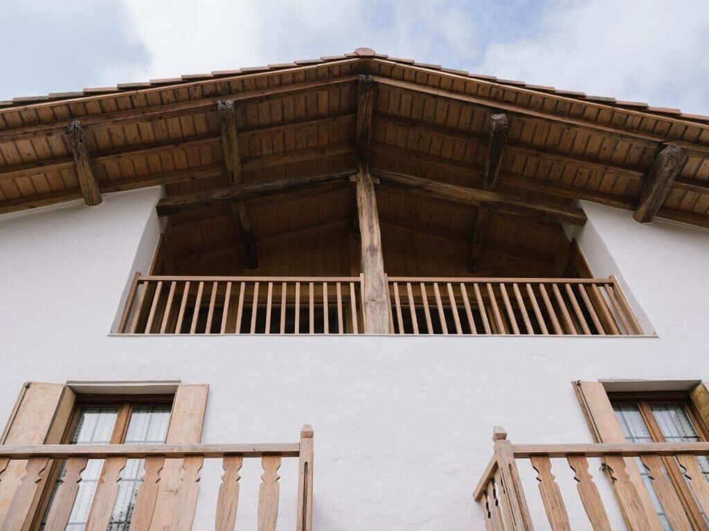 Un edifici amb un balcó de fusta i una façana blanca.
