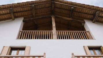 Un edifici amb un balcó de fusta i una façana blanca.