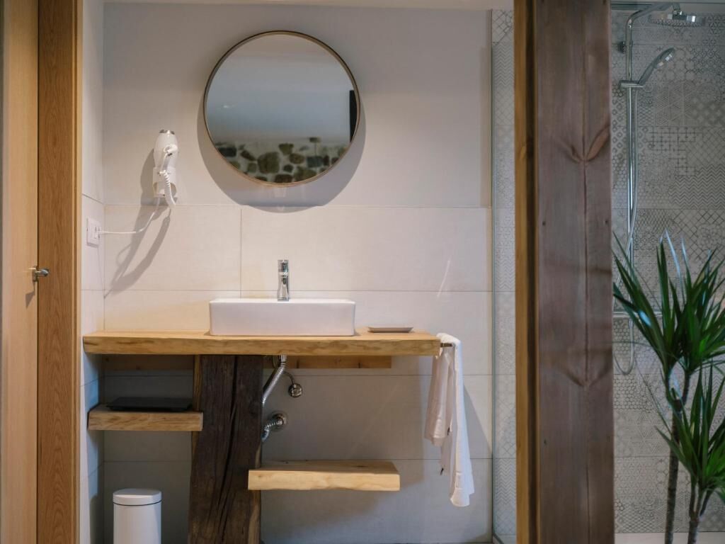 A bathroom with a wooden vanity, a round mirror, and a shower area.