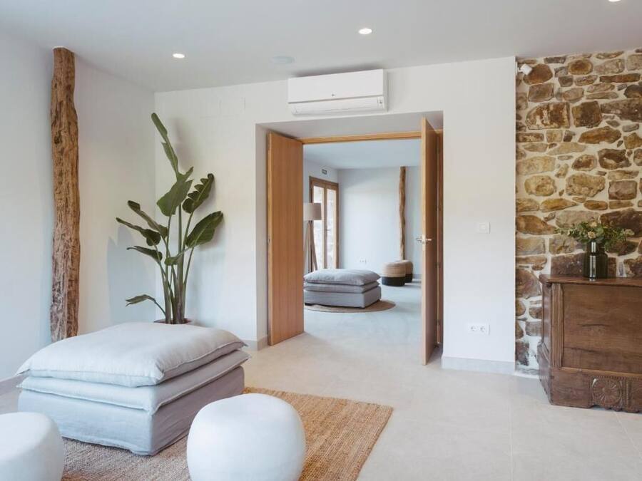 A modern room with a stone wall, a large plant, a white sofa, and a wooden cabinet.