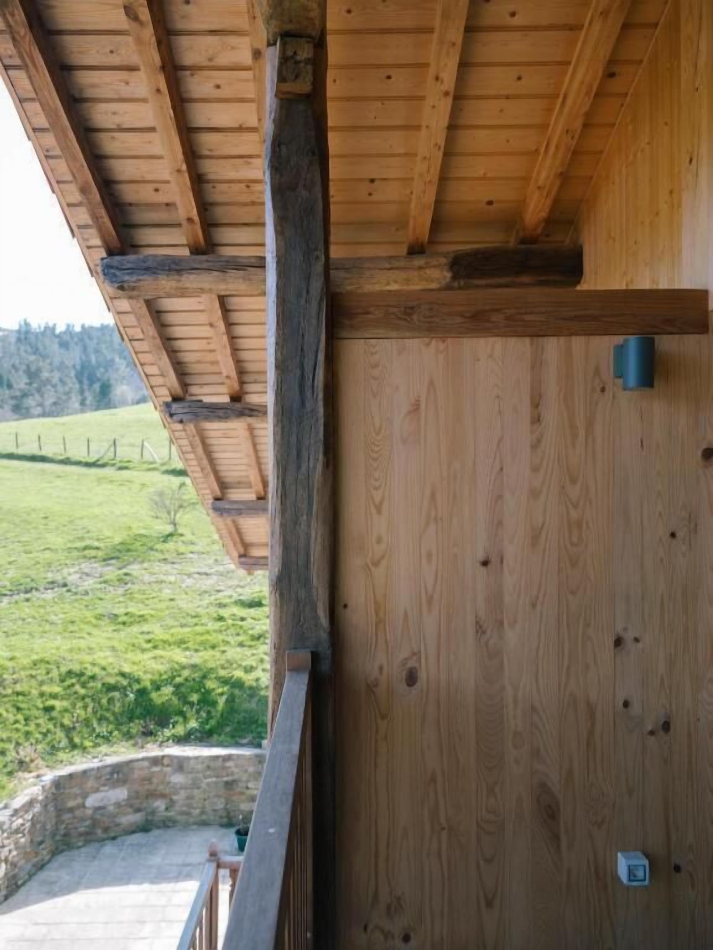 Une cabane en bois avec un toit en pente, des fondations en pierre et une vue sur un paysage verdoyant.