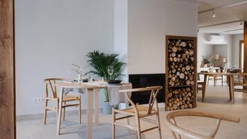 A modern dining area with wooden furniture, a fireplace, and a wall decorated with logs.