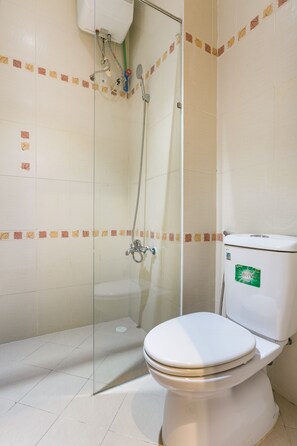 A bathroom with a toilet, a shower with a glass door, and tiled walls. - The Art - Sunshine Ben Thanh (Ho Chi Minh City)