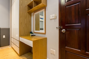 A room with a wooden desk, a mirror, a wardrobe, and a wooden door. - The Art - Sunshine Ben Thanh (Ho Chi Minh City)