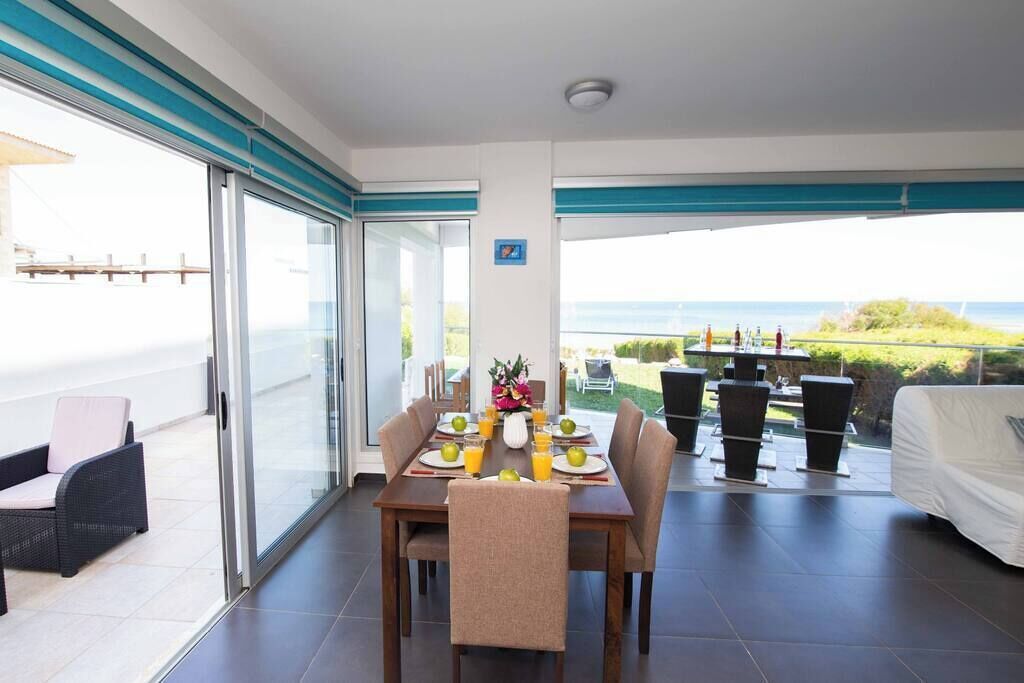 Un comedor con una mesa preparada para cuatro personas, un sofá y vista al mar.