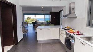 A modern kitchen with a built-in washing machine, a large island, and a view of the outdoors. - Beachfront apartmen located just a stone's throw away from Ayia Triada beach (Paralimni)
