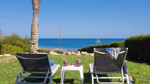 Two lounge chairs facing a beach with a clear view of the ocean. - Beachfront apartmen located just a stone's throw away from Ayia Triada beach (Paralimni)
