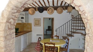 A rustic kitchen with a stone archway, wooden staircase, and a dining table with chairs. - Charming 3-bedroom home with a private pool at the foot of Mont Ventoux. Stunning view (Bédoin)