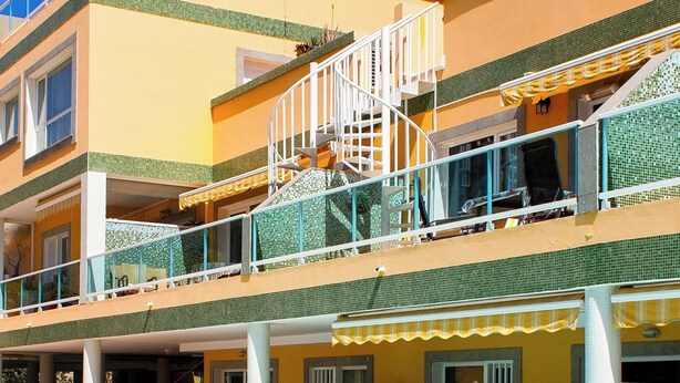 Un hotel a più piani con piscina al piano terra.