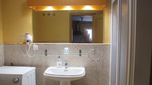 Un bagno con lavandino bianco, cabina doccia in vetro e lavatrice.