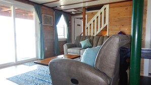 A living room with a sofa, a coffee table, and a patterned rug. There is a staircase leading to another level. - Beautiful sunsets and relaxing days, are waiting for you at Harborside  Cottage. (Tremont)