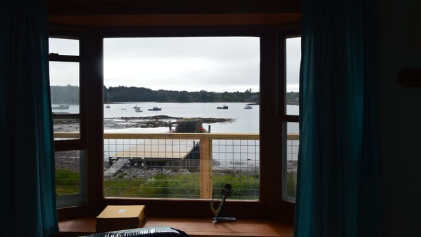A room with a large bay window overlooking a body of water with boats. - Beautiful sunsets and relaxing days, are waiting for you at Harborside  Cottage. (Tremont)