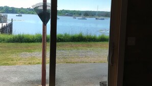 A room with a large sliding glass door leading to a view of a lake with boats. - Beautiful sunsets and relaxing days, are waiting for you at Harborside  Cottage. (Tremont)