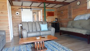 A cozy living room with a grey sofa, a wooden coffee table, and a patterned rug. - Beautiful sunsets and relaxing days, are waiting for you at Harborside  Cottage. (Tremont)