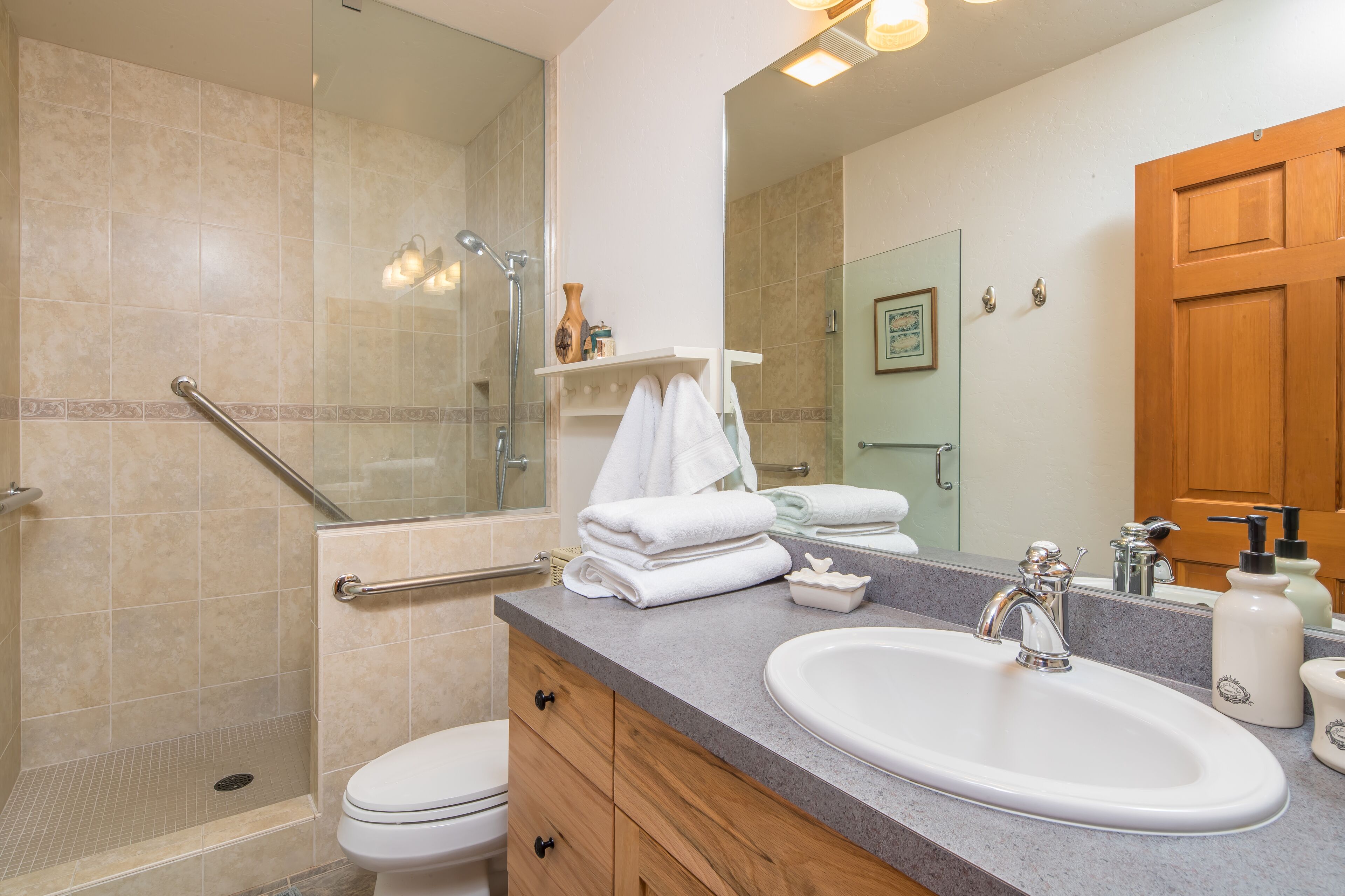 A bathroom with a shower, toilet, sink, and vanity.