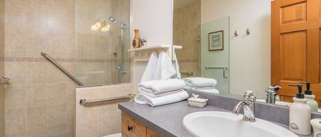 A bathroom with a shower, toilet, sink, and vanity.