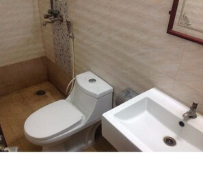 A small bathroom with a toilet, a sink, and a shower. - Hotel Coastal Residency (Namakkal)