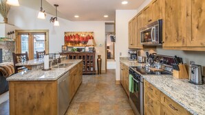 Une cuisine spacieuse dotée de plans de travail en granit, d’armoires en bois et d’un îlot central.