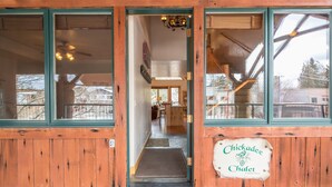 Un edificio in legno con un'insegna che riporta 'Chickadee Chalet' e un interno visibile con una sala da pranzo e una scala.