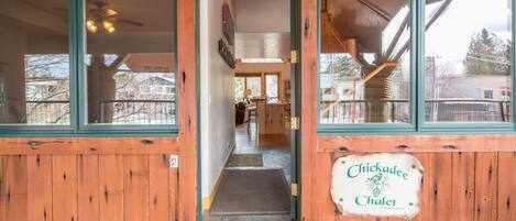 Entrada de um prédio de madeira com uma placa que diz 'Chickadee Chalet A Vacation Rental'.