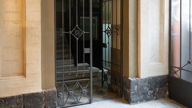 Una entrada ornamentada con una reja de metal, un arco decorativo y un suelo de baldosas.