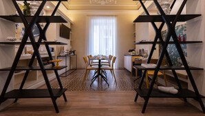 Un comedor con una mesa central, sillas alrededor y estanterías negras con adornos.
