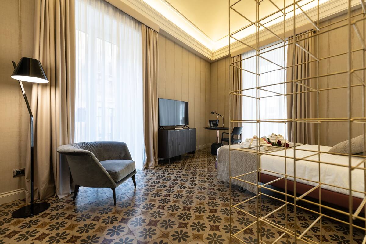 Ein Hotelzimmer mit einem Bett, einem Schreibtisch, einem Stuhl, einem Fernseher und einem Boden mit Blumenmuster.