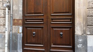 Una gran puerta doble de madera labrada con un arco de piedra encima.