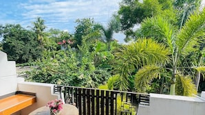 A balcony with a round table and chairs, a hanging light fixture, and a view of lush greenery. - AWON Hotel (Mirissa)