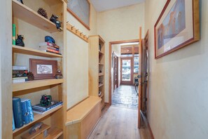 Un couloir étroit avec des étagères en bois, un banc et un tableau encadré accroché au mur.
