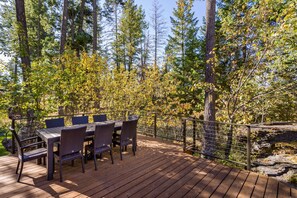 Une terrasse en bois avec une table et des chaises, entourée d’arbres.
