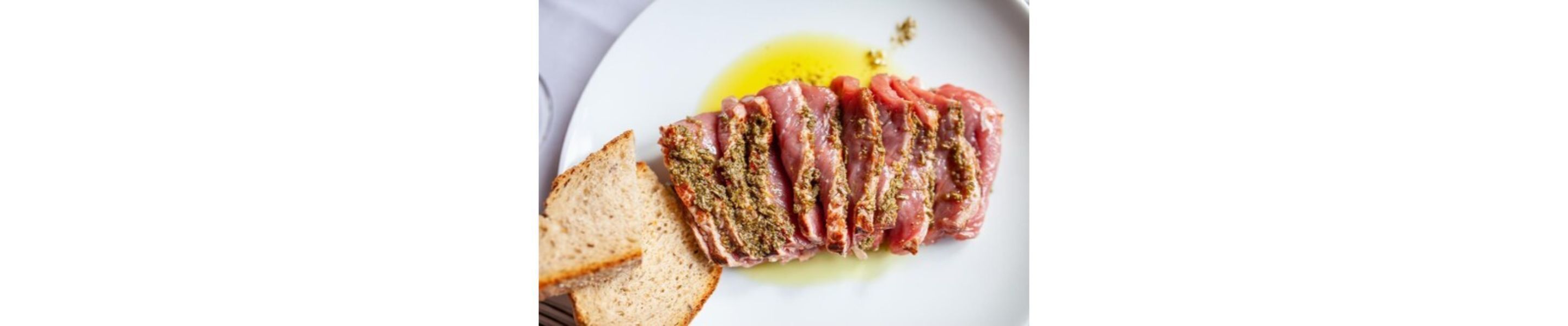 A plate with sliced meat and bread on a white background.