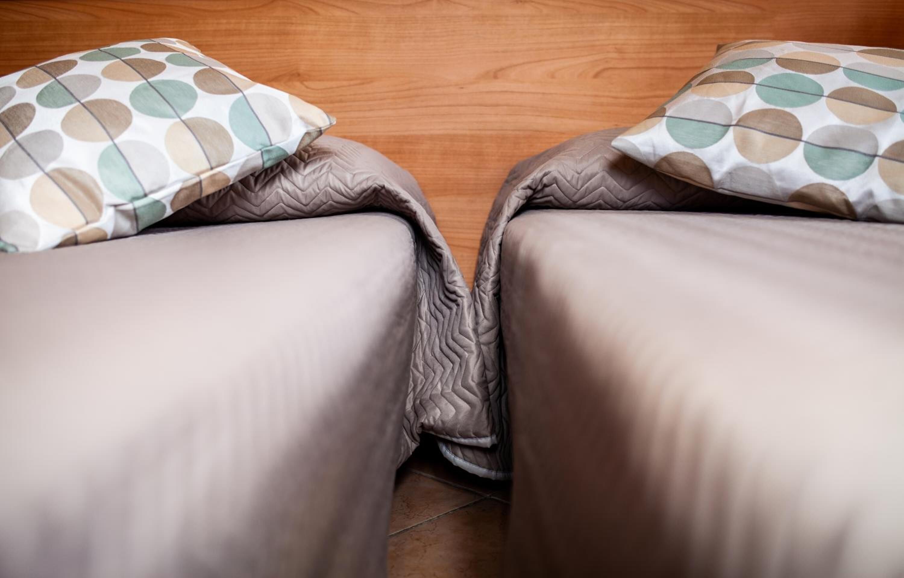 A bed with a quilted cover and two pillows with a polka dot pattern.
