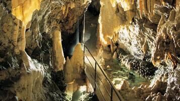 A cave with stalactites and stalagmites, a metal staircase, and a water feature.