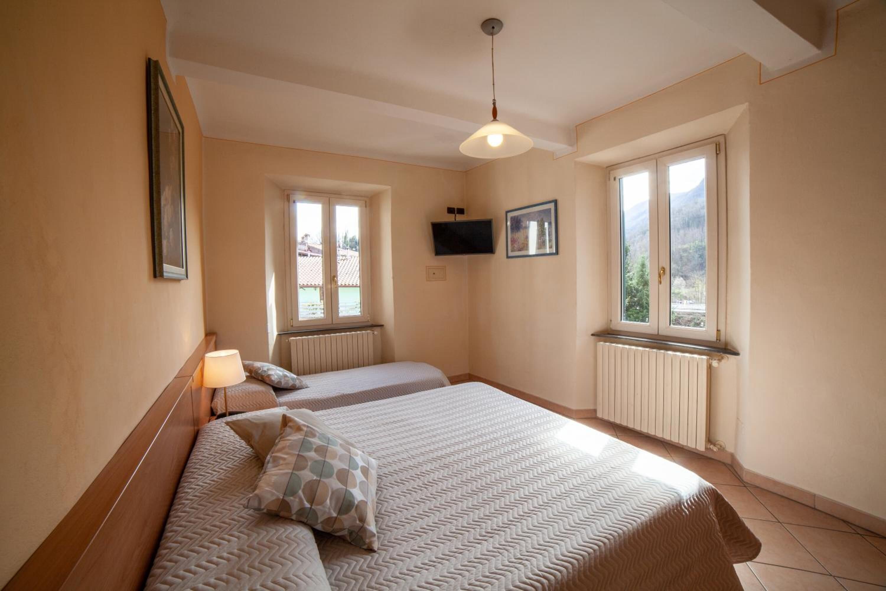 Ein Schlafzimmer mit zwei Betten, einem Deckenventilator, einem Fernseher und großen Fenstern mit Blick auf die Berge.