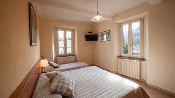 Ein Schlafzimmer mit zwei Betten, einem Deckenventilator, einem Fernseher und großen Fenstern mit Blick auf die Berge.