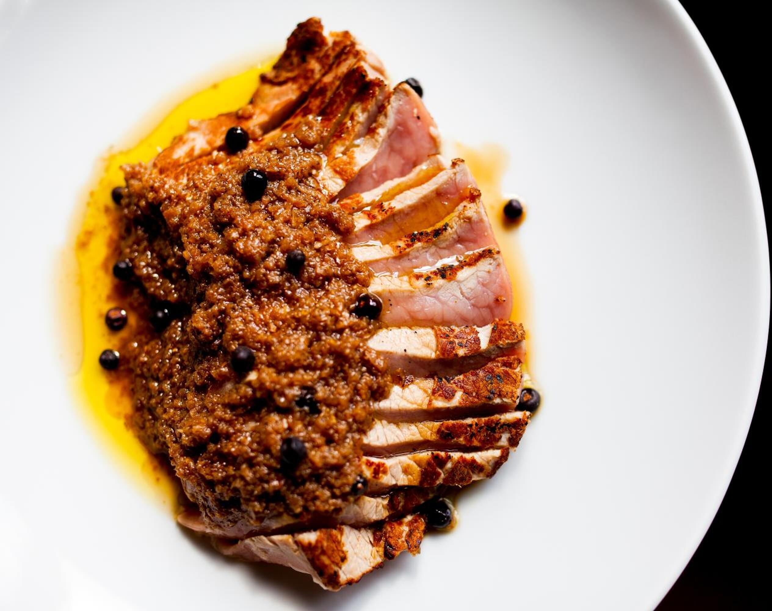Un plato con carne en rodajas y salsa marrón.