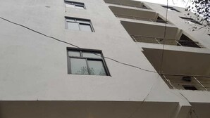 Un immeuble à plusieurs étages, doté d’une façade plane, de nombreuses fenêtres et de câbles électriques apparents.