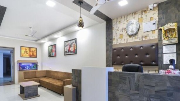 A reception area with a sofa, a fish tank, and a wall with framed artwork. - ABS Hotel (Noida)