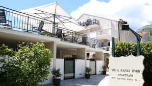 A villa with a balcony, potted plants, and a sign indicating it is an apartment. - Villa Rajski Dvor1 (Bol)