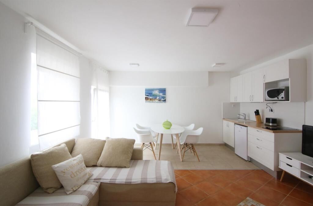 Un espacio habitable compacto con sofá, mesa de comedor y kitchenette.