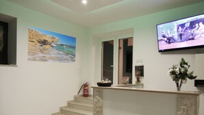 A reception area with a reception desk, a flat-screen TV, a painting on the wall, and a staircase leading to another room. - Villa Rajski Dvor1 (Bol)
