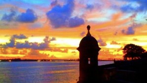 La silhouette d’un bâtiment coiffé d’un dôme, se détachant sur un ciel au coucher du soleil.
