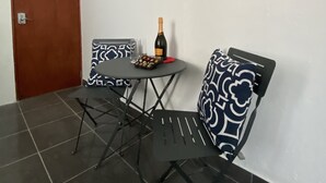 Un petit coin repas avec une table, des chaises, une bouteille de vin et un tableau encadré au mur.