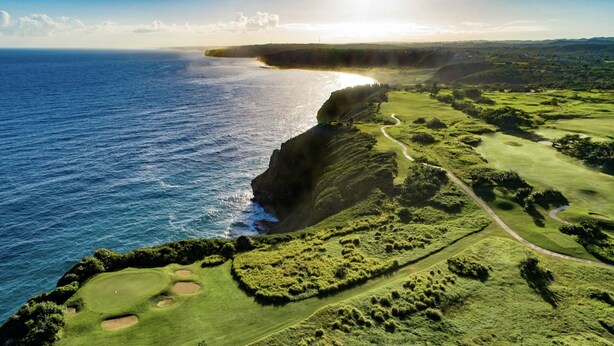 Un parcours de golf situé sur la côte, offrant une vue sur l’océan et bordé d’une route sinueuse.