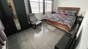 Une chambre à coucher avec un lit, une chaise, une armoire, une fenêtre et une porte.