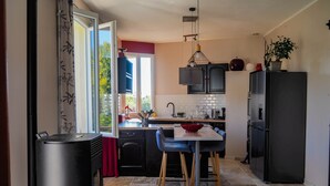 A modern kitchen with a central island, black cabinets, and a large refrigerator. - Les Gîtes de L'Aven - la Forestiere (Orgnac L'aven)